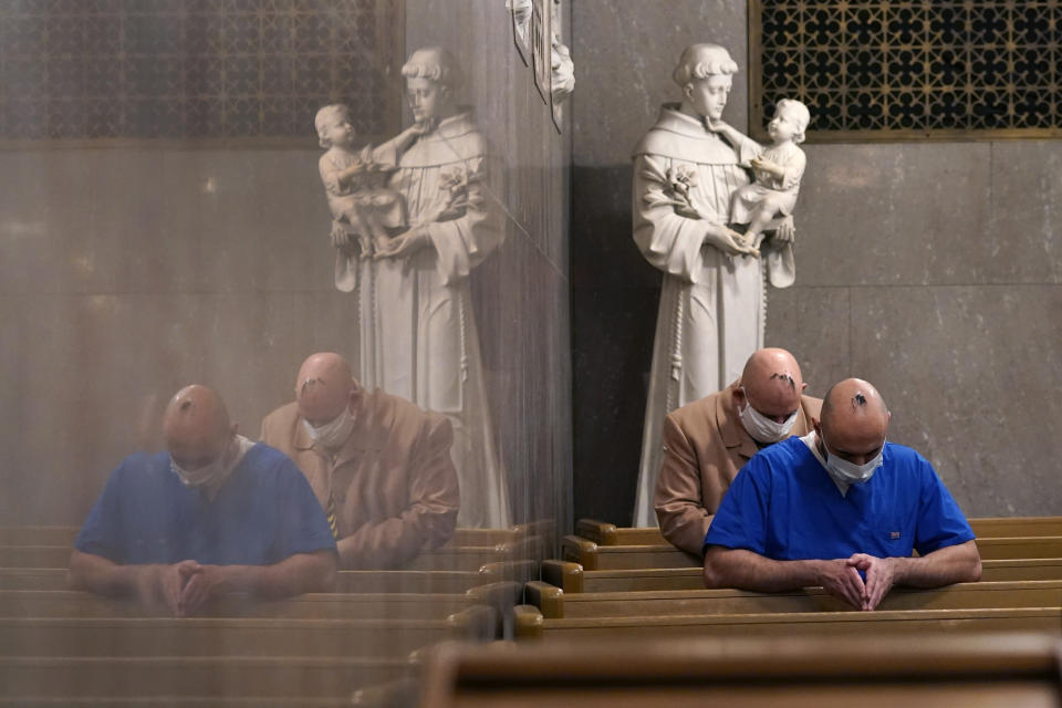 Sanar Yokhana, foreground, and Richard Lewandowski pray in front of a statue of St. Anthony during an Ash Wednesday service at the St. Aloysius Catholic Church, Wednesday, Feb. 17, 2021, in Detroit. The ashes, a symbol of penance, are made from palm leaves used in last year's Palm Sunday liturgy and were sprinkled on their head. The sprinkling, because of the pandemic, is a departure from the usual practice of making the sign of the cross on the forehead and follows an ancient method still common in parts of the world today. (AP Photo/Carlos Osorio)