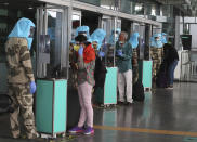 Indian security personnel wearing protective gear interact with passengers through glass before allowing them inside the departure terminal at Kempegowda International Airport in Bengaluru, India, Tuesday, June 2, 2020. More states opened up and crowds of commuters trickled onto the roads in many of India's cities on Monday as a three-phase plan to lift the nationwide coronavirus lockdown began despite an upward trend in new infections. (AP Photo/Aijaz Rahi)