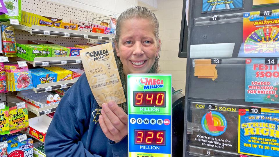 Teresa Morgan, the manager of the Citgo gas station in Belleville, Wisconsin, holds up a Mega Millions lottery ticket on Thursday. The Mega Millions jackpot has swelled to an estimated $940 million.