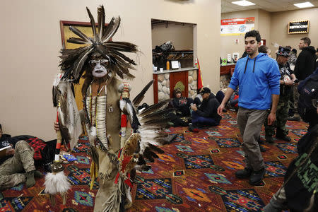 A Native American dancer walks past activists and veterans who are sheltering at the Prairie Knights Casino because of a blizzard hitting the Standing Rock Indian Reservation, near Fort Yates, North Dakota, U.S., December 6, 2016. REUTERS/Lucas Jackson