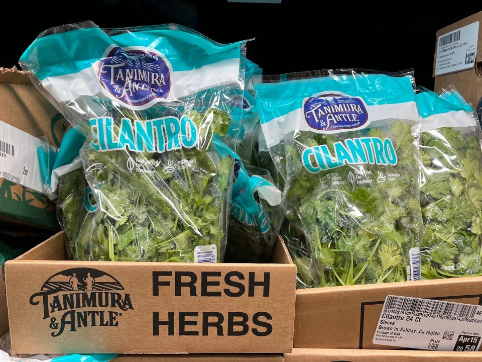 Bags of cilantro in cardboard boxes that read "Tanimura & Antle Fresh Herbs."