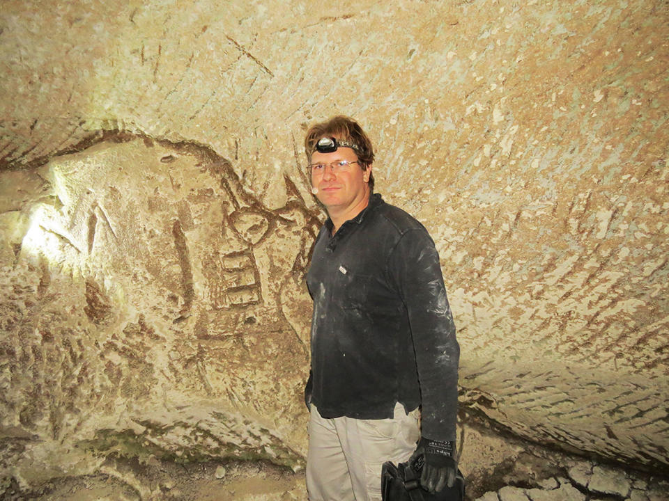 Hiker Ido Meroz stands next to a wall engraving, which appears to depict a key. <cite>Mickey Barkal</cite>