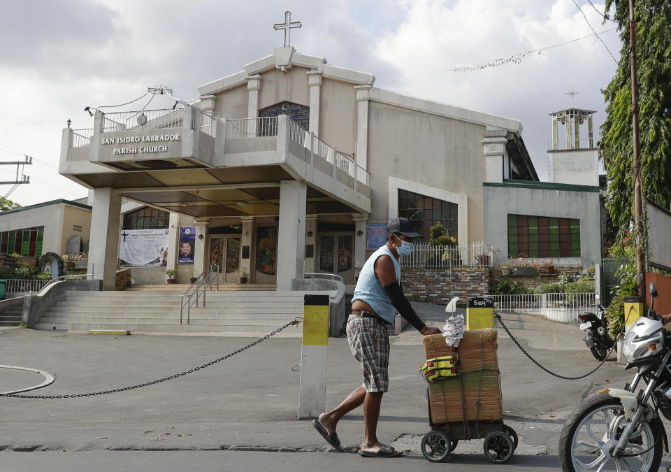 A vendor wearing a protective mask walks past a church in suburban Quezon city, in Manila, Philipines on Saturday March 14, 2020. Masses at churches in metropolitan Manila have been suspended as a precautionary measure against the spread of the new Coronavirus. Philippine officials on Saturday declared a night curfew in the capital and said millions of people in the densely populated region could only go out of their homes for work, buy necessities and medical emergencies at daytime under a monthlong quarantine to be imposed to fight the new coronavirus. (AP Photo/Aaron Favila)