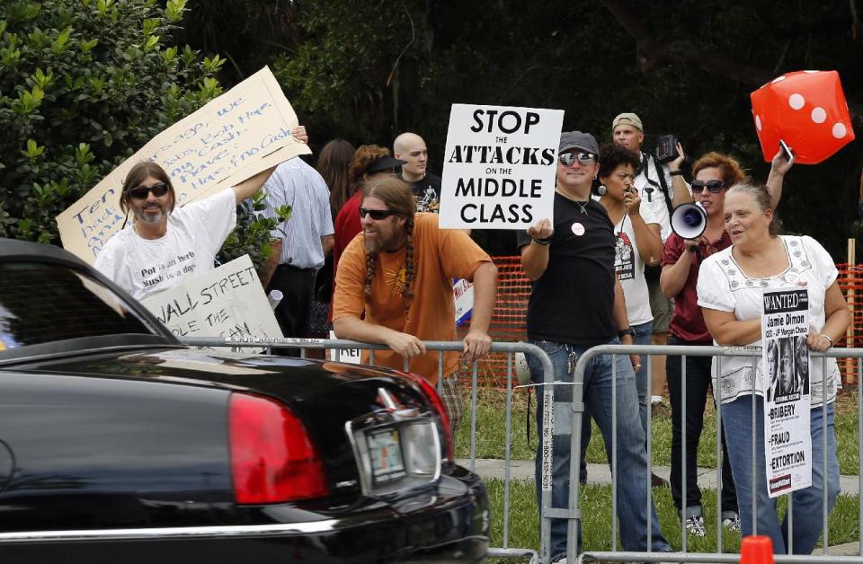 Protestors stand outside the gate of JPMorgan Chase after the annual stockholders meeting held Tuesday, May 15, 2012, in Tampa, Fla. CEO Jamie Dimon kept his job after he disclosed a $2 billion trading loss by the bank. (AP Photo/Scott Iskowitz)