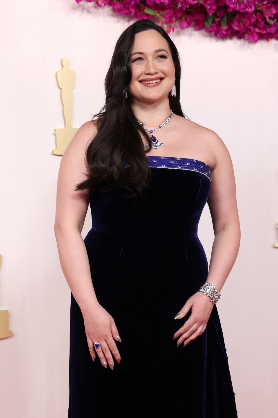 Lily Gladstone in a velvet strapless gown posing on the red carpet