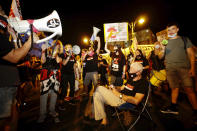 Israeli protesters hold signs and chant slogans during a demonstration against Israeli Prime Minister Benjamin Netanyahu near the Prime Minister's residence in Jerusalem, Sunday, Sept. 20, 2020. (AP Photo/Sebastian Scheiner)