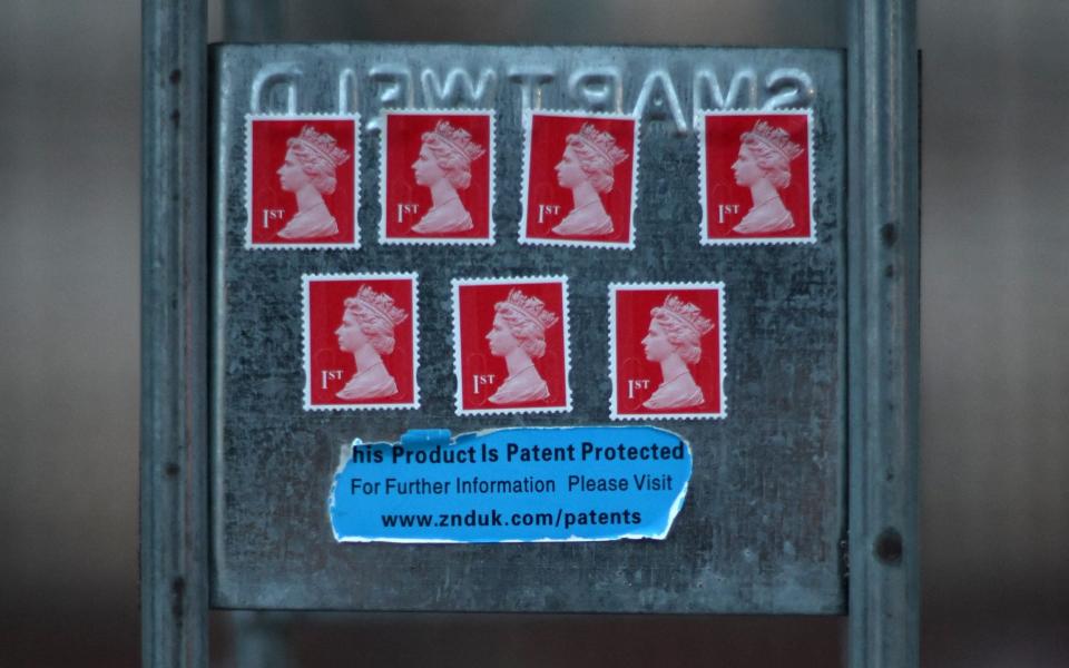 A tribute in the form of 1st class stamps bearing the image of Queen Elizabeth II is stuck to railings outside of Buckingham Palace in London the day after her death - Daniel LEAL / AFP