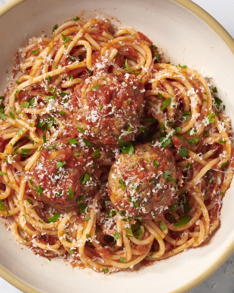 spaghetti and meatballs in bowl garnished