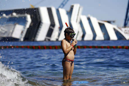 A boy prepares to snorkel in front of the wreckage of capsized cruise liner Costa Concordia, near the harbour of Giglio Porto August 28, 2012. REUTERS/Alessandro Bianchi