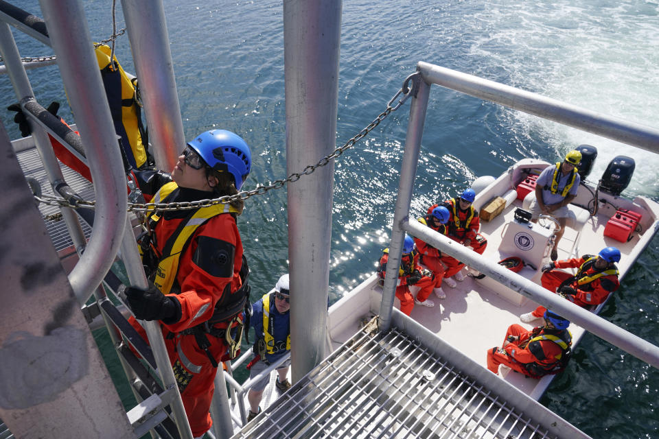 Ellen Crivella, left, and other participants learn how to get from a boat to the tower of an off shore wind turbine during a Global Wind Organisation certification class at the Massachusetts Maritime Academy in Bourne, Mass., Thursday, Aug. 4, 2022. At the 131-year-old maritime academy along Buzzards Bay, people who will build the nation's first commercial-scale offshore wind farm are learning the skills to stay safe while working around turbines at sea. (AP Photo/Seth Wenig)