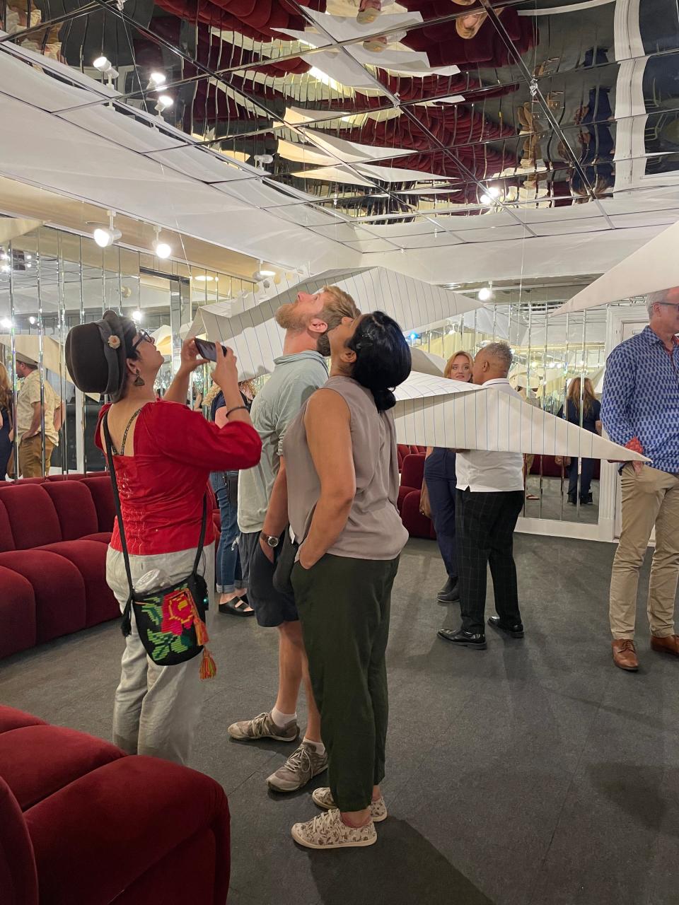 Attendees to the opening reception for Michael Scoggins' Goose at Laney Contemporary gaze at oversized paper airplanes.