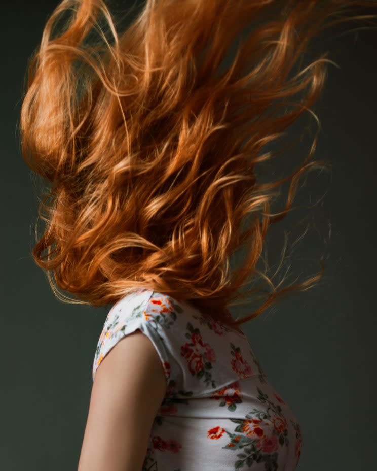 A model's face is obscured by her red hair.