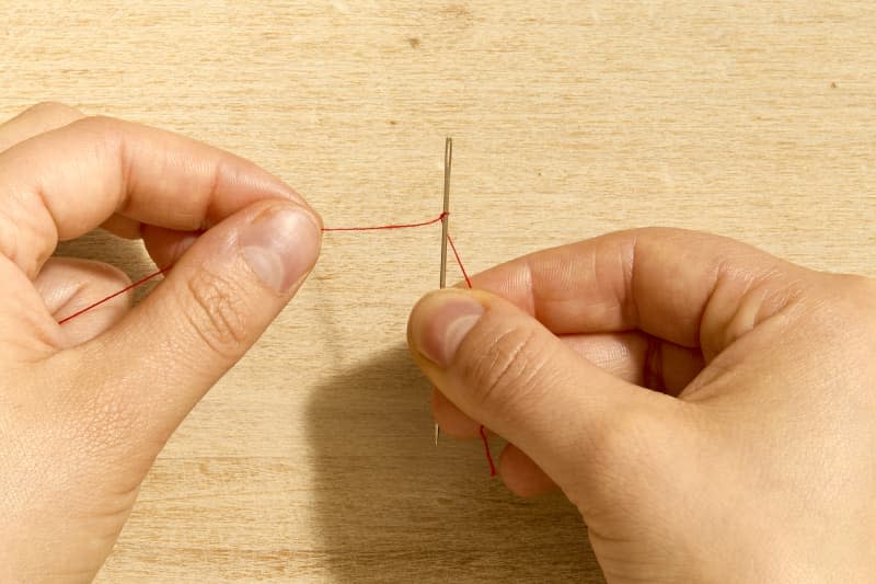 shot of a needle being threaded using the knot method.