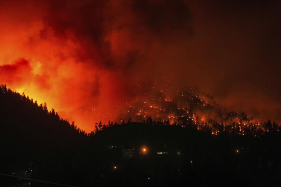 The McDougall Creek wildfire burns on the mountainside above houses in West Kelowna, B.C., on Friday, Aug. 18, 2023. Thousands have fled, driving hundreds of kilometers (miles) to safety or waiting in long lines for emergency flights, as the worst fire season on record in Canada showed no signs of easing. (Darryl Dyck /The Canadian Press via AP)