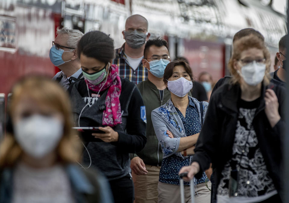 Passengers with face masks arrive in the main train station in Frankfurt, Germany, Thursday, Aug. 27, 2020. An announcement of German Chancellor Angela Merkel about the further strategy to avoid the outspread of the Coronavirus is expected later today. (AP Photo/Michael Probst)