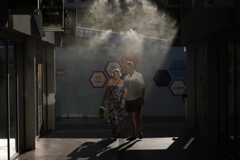 People walk through cooling misters along the Las Vegas Strip, Thursday, July 13, 2023, in Las Vegas. Even desert residents accustomed to scorching summers are feeling the grip of an extreme heat wave smacking the Southwest this week. Arizona, Nevada, New Mexico and Southern California are getting hit with 100-degree-plus temps and excessive heat warnings. (AP Photo/John Locher)