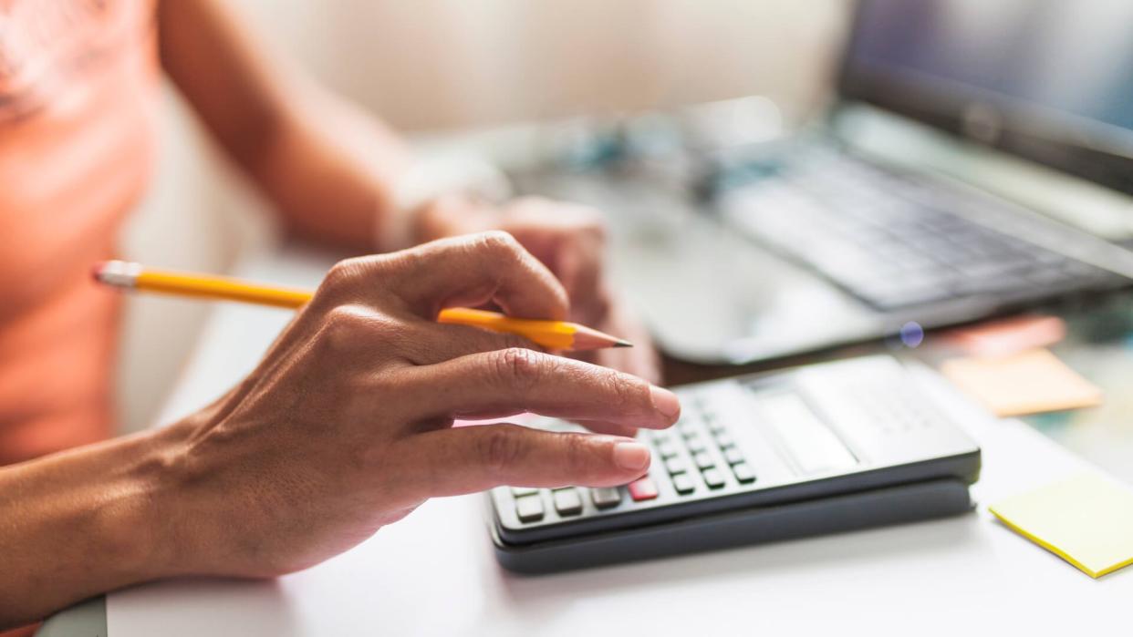 Hands with pencil punching in digits on calculator