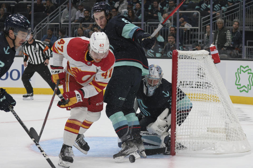 Calgary Flames forward Connor Zary (47) attacks the net as Seattle Kraken defenseman Cale Fleury and goalie Philipp Grubauer defend during the first period of a preseason NHL hockey game Tuesday, Sept. 27, 2022, in Seattle. (AP Photo/Jason Redmond)