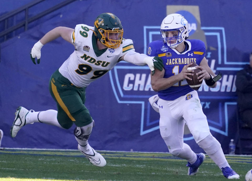 CORRECTS TO NORTH DAKOTA STATE NOT NORTH DAKOTA TXMO101-116 - South Dakota State quarterback Mark Gronowski (11) eludes North Dakota State defensive end Spencer Waege (99) during the first half of the FCS Championship NCAA college football game Sunday, Jan. 8, 2023, in Frisco, Texas. (AP Photo/LM Otero)