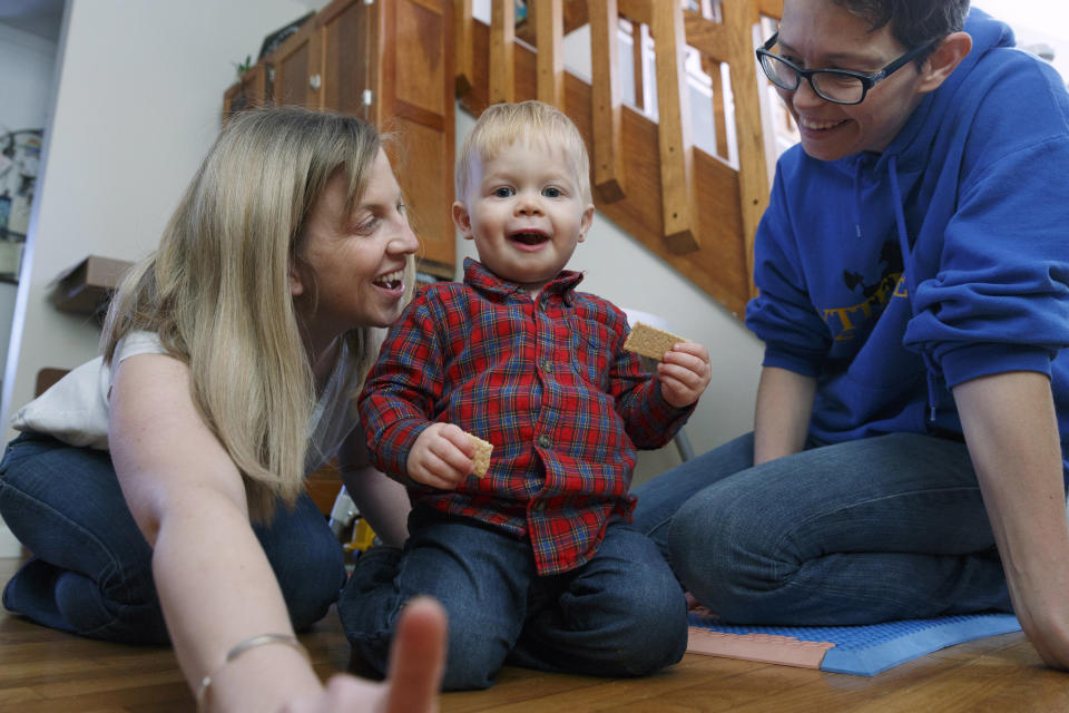 In this Friday, Nov. 16, 2018, photo, Anna Ford, left, and her partner, Sara Watson, play with their son Eli at home in the village of Saunderstown, in Narragansett, R.I. Three years after the landmark U.S. Supreme Court case that gave same-sex couples the right to marry nationwide, a patchwork of outdated state laws governing who can be a legal parent presents obstacles for many LGBTQ couples who start a family, lawyers say. (AP Photo/Michael Dwyer)