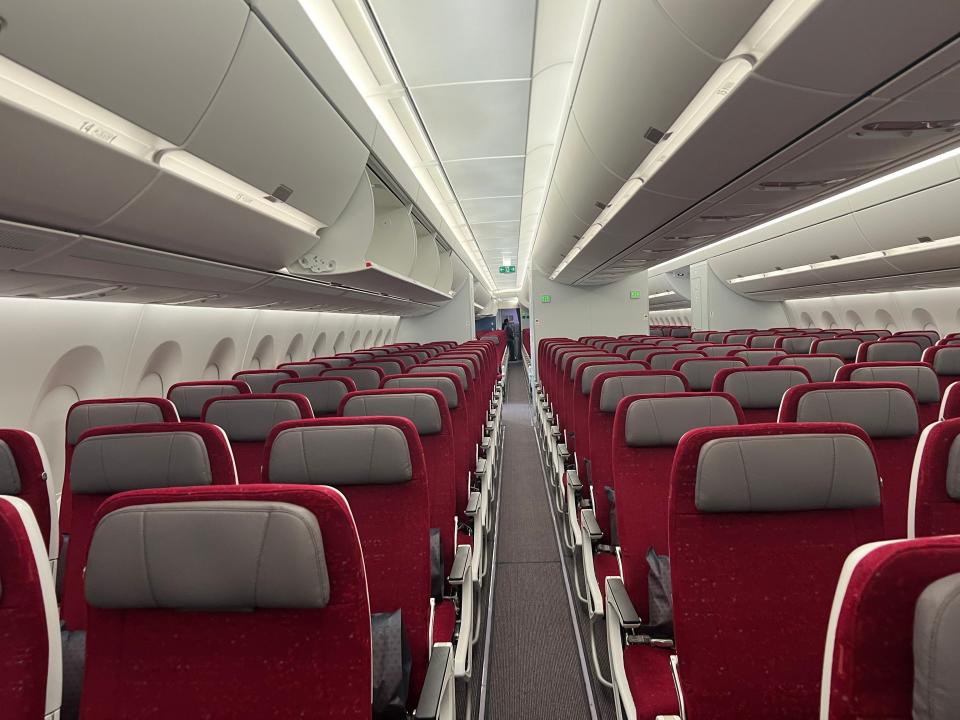 New economy cabin on Air India with red seats and grey headrests.
