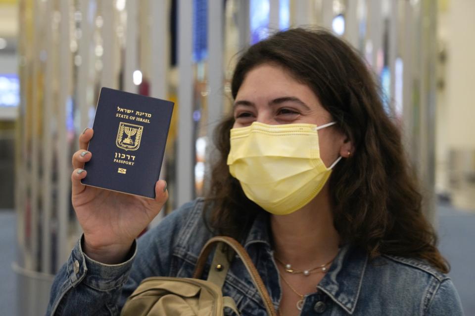 FILE - In this Nov. 26, 2020 file photo, an Israeli passenger from a flyDubai flight from Tel Aviv, Israel, waves her Israeli passport on arrival at Dubai International Airport's Terminal 3 in Dubai, United Arab Emirates. Travel agencies in countries across the Middle East and Africa say the United Arab Emirates has temporarily halted issuing new visas to their citizens, a so-far unexplained ban on visitors amid both the coronavirus pandemic and as the UAE normalizes ties with Israel. (AP Photo/Jon Gambrell, File)