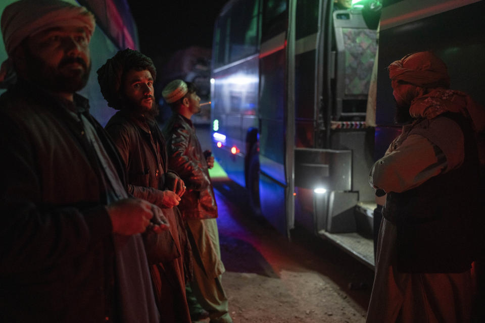 Afghan men wait to embark at a bus station in Herat, Afghanistan, Monday, Nov. 22, 2021, for a 300-mile trip south to Nimrooz near the Iranian border. Afghans are streaming across the border into Iran, driven by desperation after the near collapse of their country's economy following the Taliban's takeover in mid-August. In the past three months, more than 300,000 people have crossed illegally into Iran, according to the Norwegian Refugee Council, and more are coming at the rate of 4,000 to 5,000 a day. (AP Photo/Petros Giannakouris)