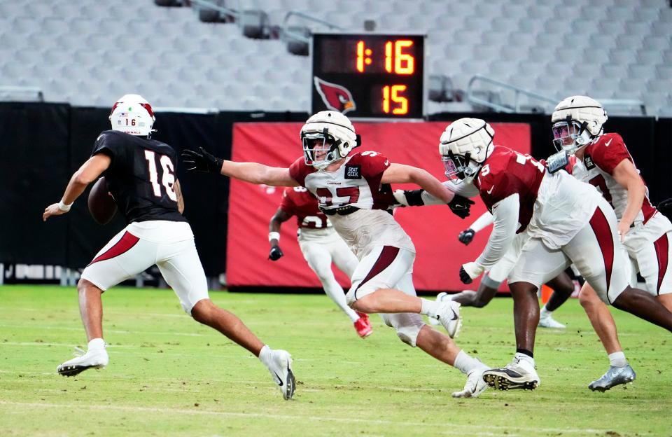 Aug 9, 2022; Glendale, Arizona, USA; Arizona Cardinals quarterback Jarrett Guarantano (16) is chased by linebacker Cameron Thomas (97) during training camp at State Farm Stadium.