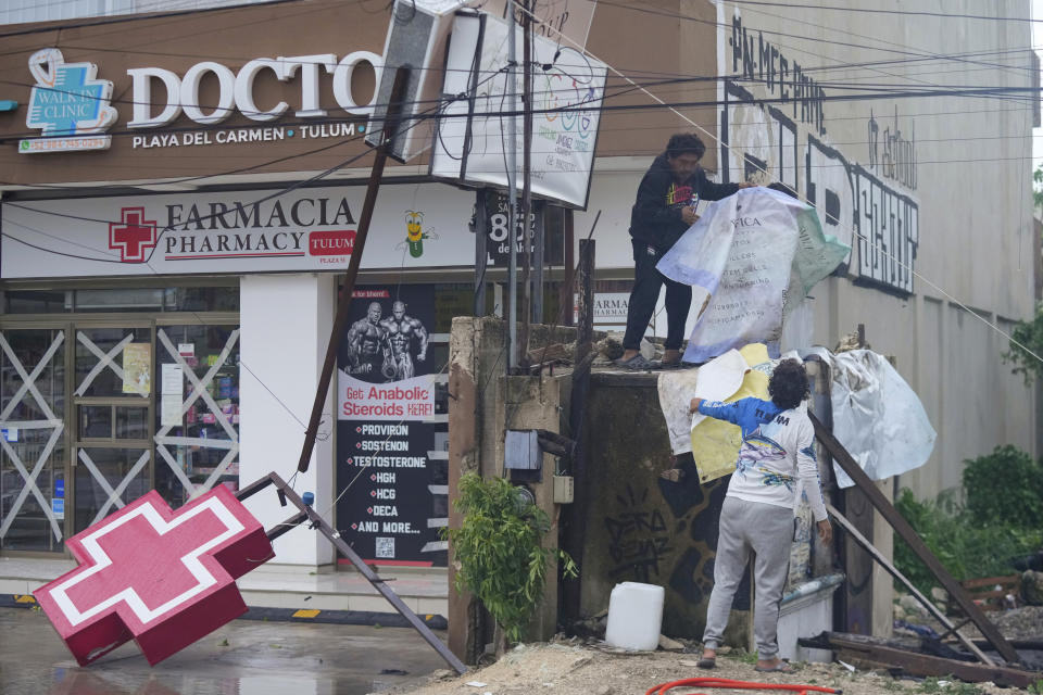 Residents clean up the entrance of a drugstore damaged by Hurricane Beryl in Tulum, Mexico, Friday, July 5, 2024. (AP Photo/Fernando Llano)