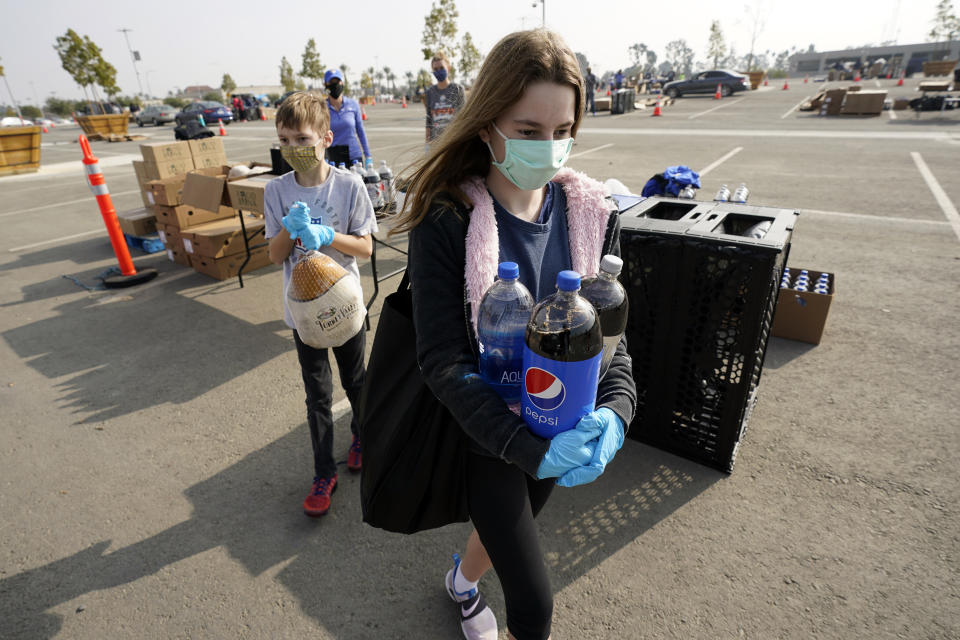 Claire Demoff, 13, foreground, and her brother Owen, 11, volunteer at a food distribution center set up at SoFi Stadium amid the COVID-19 pandemic and ahead of Thanksgiving, Monday, Nov. 23, 2020, in Inglewood, Calif. (AP Photo/Marcio Jose Sanchez)