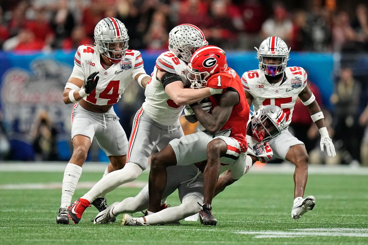 Dec 31, 2022; Atlanta, Georgia, USA; Ohio State Buckeyes cornerback Cameron Brown (26) and linebacker Tommy Eichenberg (35) stop Georgia Bulldogs wide receiver Marcus Rosemy-Jacksaint (1) during the first half of the Peach Bowl in the College Football Playoff semifinal at Mercedes-Benz Stadium. Mandatory Credit: Adam Cairns-The Columbus Dispatch