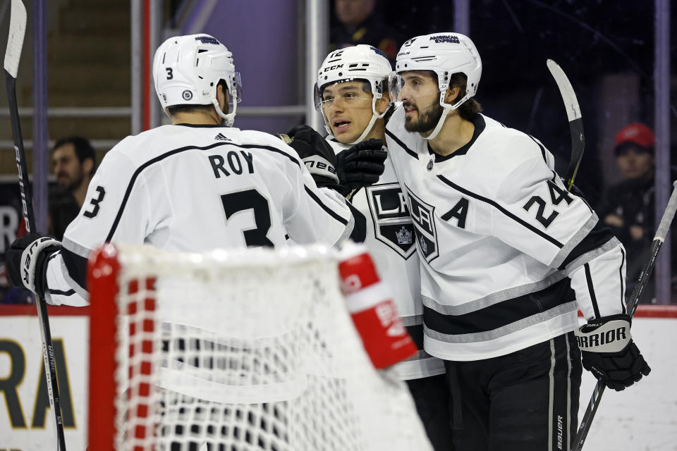 Los Angeles Kings' Trevor Moore, center, celebrates after his goal with teammates Phillip Danault (24) and Matt Roy (3) during the first period of an NHL hockey game against the Carolina Hurricanes in Raleigh, N.C., Monday, Jan. 15, 2024. (AP Photo/Karl B DeBlaker)