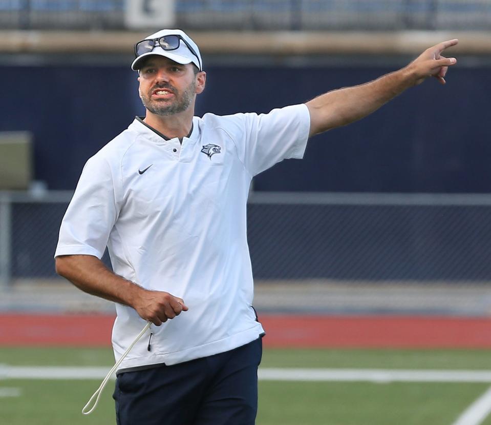 University of New Hampshire head football coach Rick Santos directs youngsters to positions during a youth football camp in Durham Tuesday.