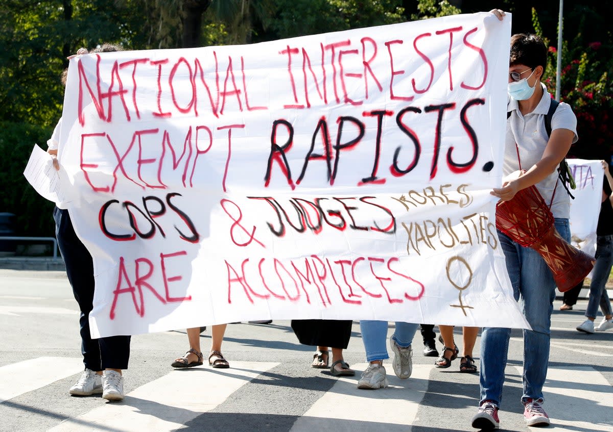 Protesters hold a banner in support of a British woman who  appealed her conviction for making false claims that she was gang raped at a resort on the island in 2019  (AP)