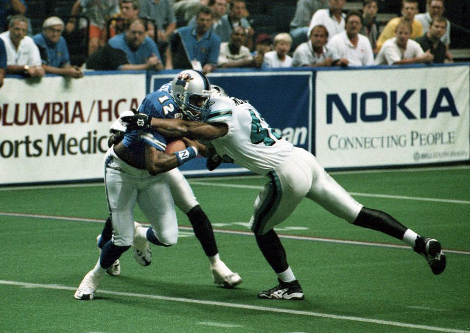 Nashville Kats receiver Cory Fleming (12) attempts to break free of a couple Florida Bobcats defenders, including Otis Mounds (42), during the Arena Football League action at the Nashville Arena June 26, 1998. Fleming had two touchdown catches from quarterback Andy Kelly in their 49-46 victory.