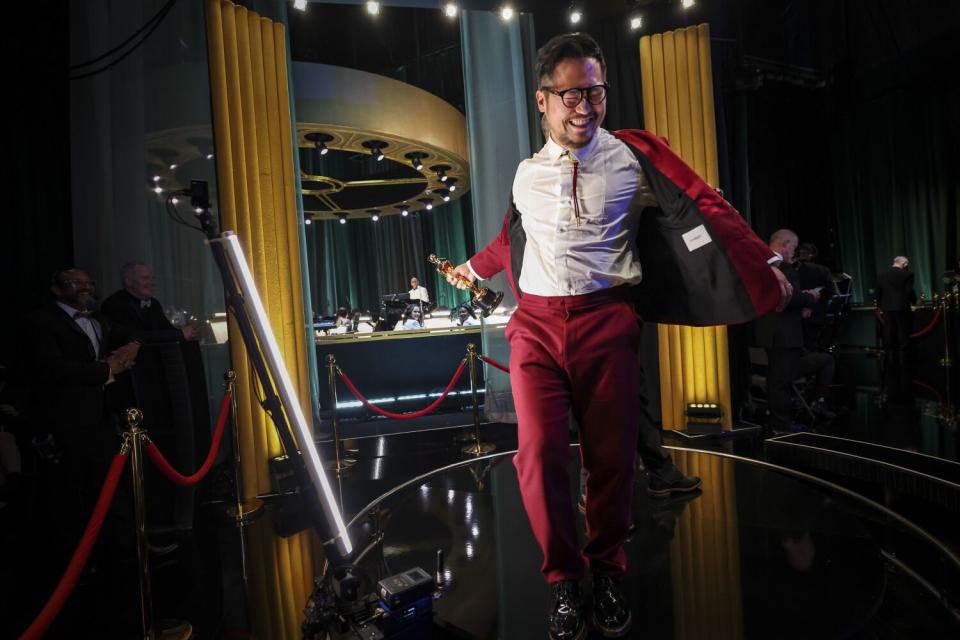 A man in a red suit shows off his white shirt backstage at the Oscars.