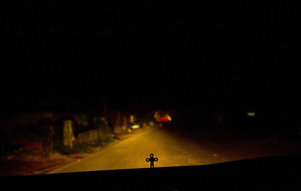 In this Thursday, Nov. 8, 2018, photo, a person drives in the night as a crucifix is seen on the dashboard in Kottayam in the southern Indian state of Kerala. For decades, nuns in India have quietly endured sexual pressure from Catholic priests, an AP investigation has revealed. (AP Photo/Manish Swarup)