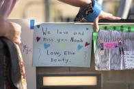 A woman adjusts notes from children before a memorial service and prayer vigil for the Lesslie family at Fountain Park, Sunday, April 11, 2021, in Rock Hill, S.C. Dr. Robert Lesslie and his wife, Barbara Lesslie, their grandchildren Adah Lesslie and Noah Lesslie, and two men working at the Lesslie home, Robert Shook and James Lewis, were fatally shot last week by former NFL player Phillip Adams. (AP Photo/Sean Rayford)