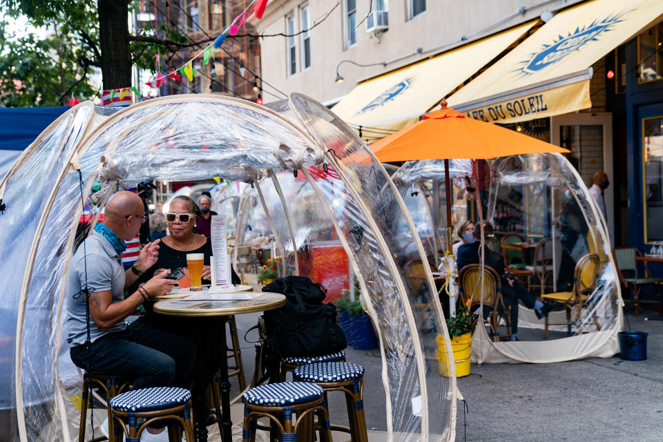 People sit outside Cafe Du Soleil under bubble tents (Jeenah Moon / Reuters)