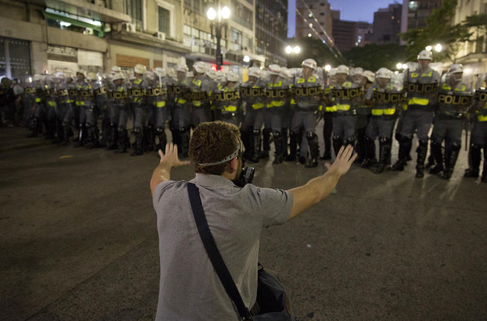 A man confronts riot police during a protest against the upcoming World Cup soccer tournament in Sao Paulo, Brazil, Saturday, Feb. 22, 2014. Hundreds of protesters gathered demonstrating against the billions of dollars being spent to host this year's World Cup while the nation's public services remain in a woeful state. The protest started peacefully, but adherents to the Black Block anarchist tactics vandalized banks and clashed with police, who used tear gas and stun grenades to disperse the violent demonstrators.(AP Photo/Andre Penner)