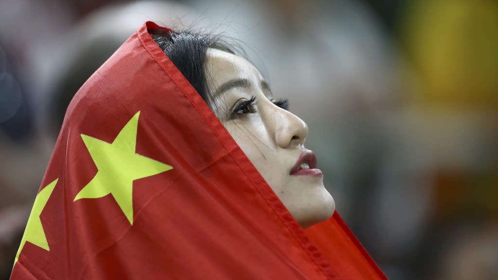 A supporter wraps herself in a Chinese flag after China won the bronze at the men's team finals.