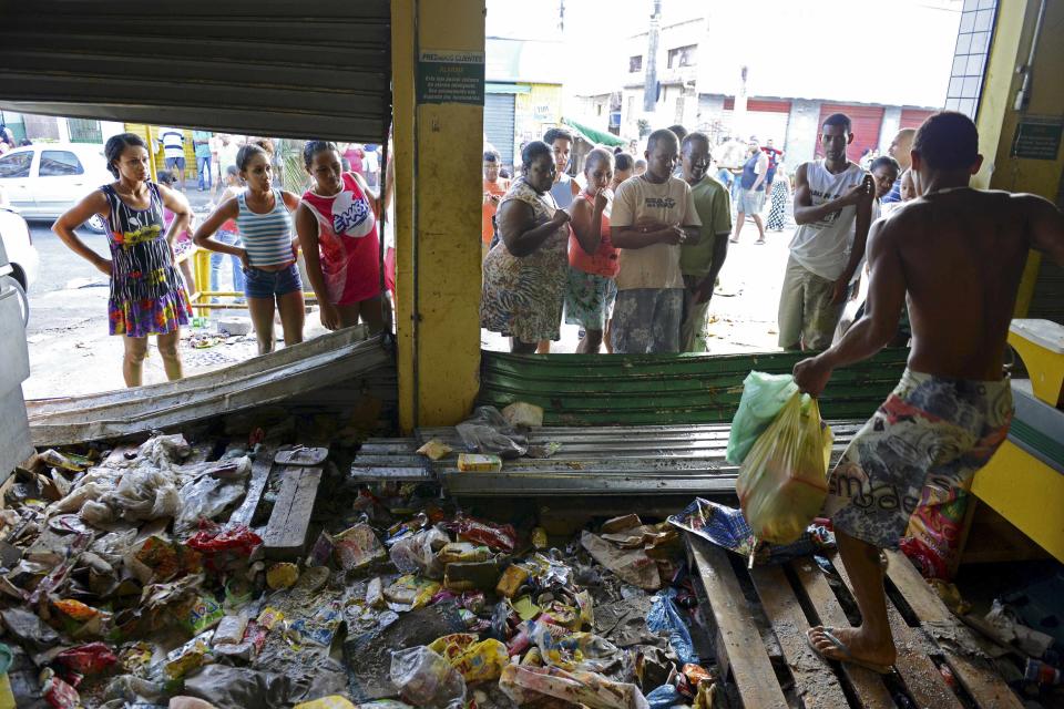 A man carries goods out of a supermarket that was looted during a police strike in Salvador, Bahia state, April 17, 2014. A police strike has unleashed violent crime in Brazil's third-largest city just two months before it is set to welcome hordes of soccer fans for the World Cup, adding to fears about the country's ability to ensure safety during the event. At least 22 people were killed in and around the northeastern city of Salvador after state police went on strike early on Wednesday to demand better pay and other benefits, the Bahia state government said on Thursday, prompting the federal government to dispatch troops to restore order. REUTERS/Valter Pontes (BRAZIL - Tags: CRIME LAW POLITICS CIVIL UNREST)