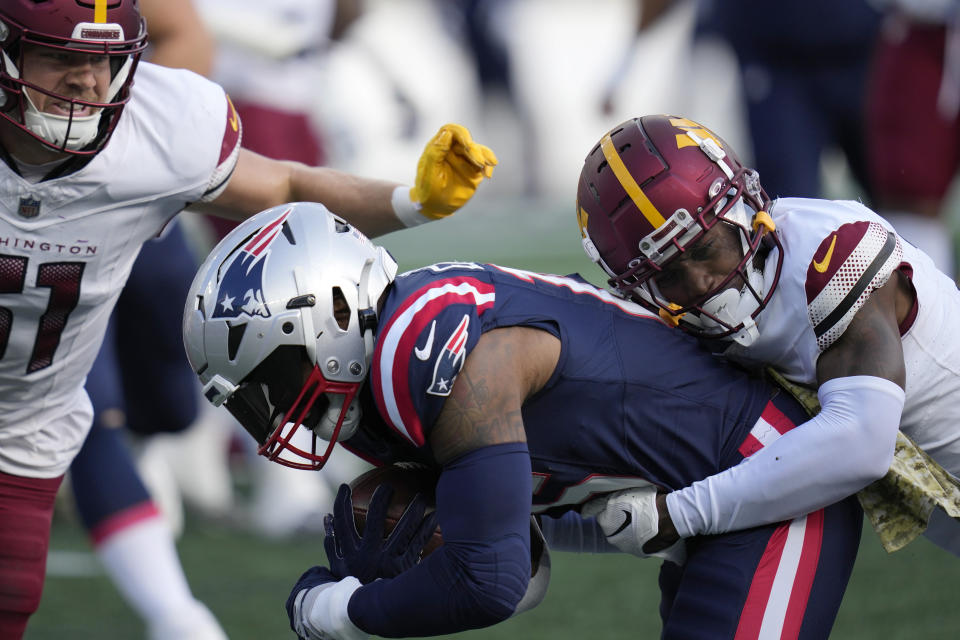 New England Patriots running back Ezekiel Elliott, center, is brought down by Washington Commanders safety Kamren Curl as linebacker David Mayo, left, defends in the first half of an NFL football game, Sunday, Nov. 5, 2023, in Foxborough, Mass. (AP Photo/Charles Krupa)