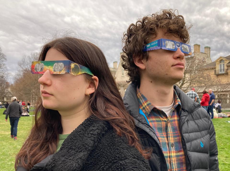 Delawareans Sascha and James Bretzger model eclipse glasses they wouldn't end up needing under cloudy skies at the George Eastman Museum in Rochester, New York during the museum's eclipse watch event, Monday, April 8, 2024.