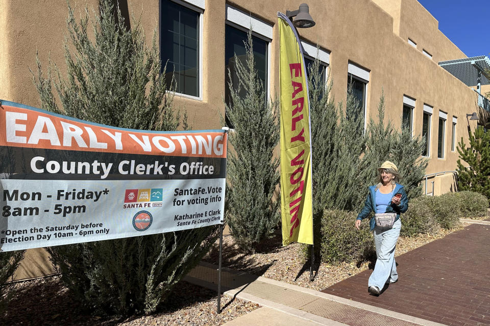 Pedestrians pass by a polling location in Santa Fe, N.M., on Thursday, Nov. 2, 2023. Voters are deciding whether to tax mansions to pay for affordable housing initiatives in a state capital city prized for its desert-mountain vistas, vibrant arts scene and stucco architecture rooted in Native American and Spanish-colonial tradition. (AP Photo/Morgan Lee)