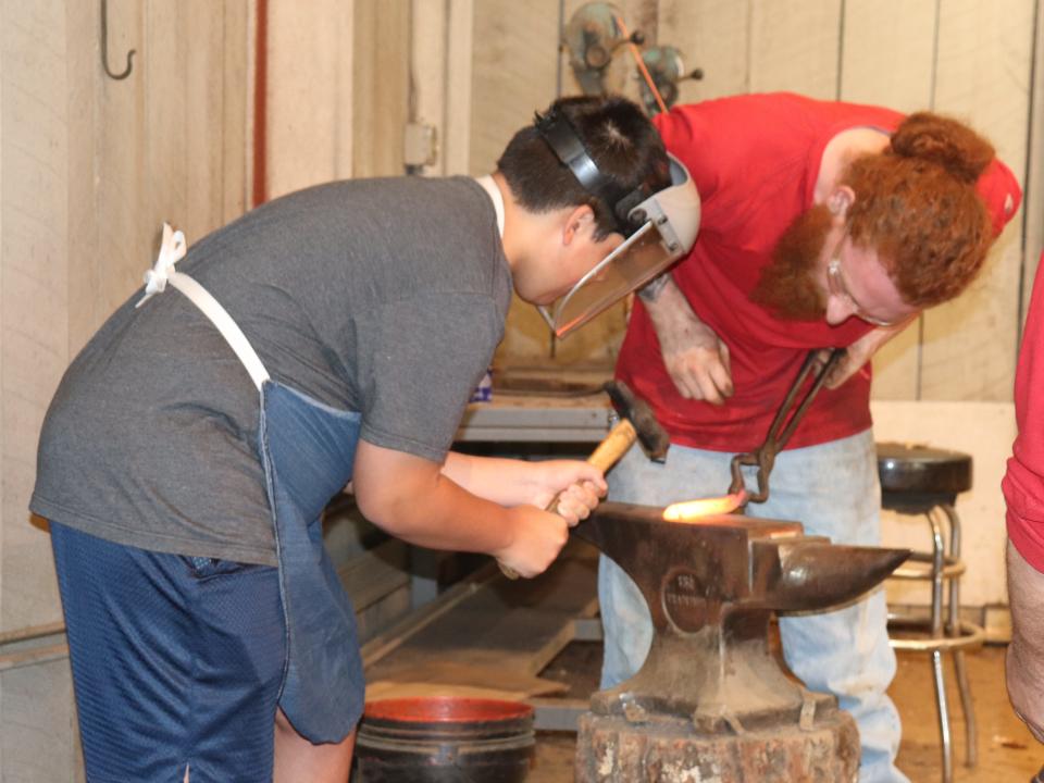 A boy hammers a piece of metal at a blacksmith activity at Dollywood