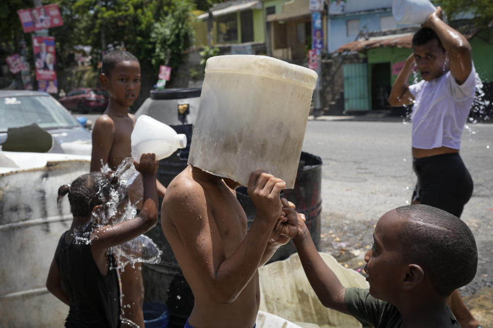 A child covers his head with a bucket in the Los Guandules neighborhood of Santo Domingo, Dominican Republic, May 20, 2024. (AP Photo/Matias Delacroix)