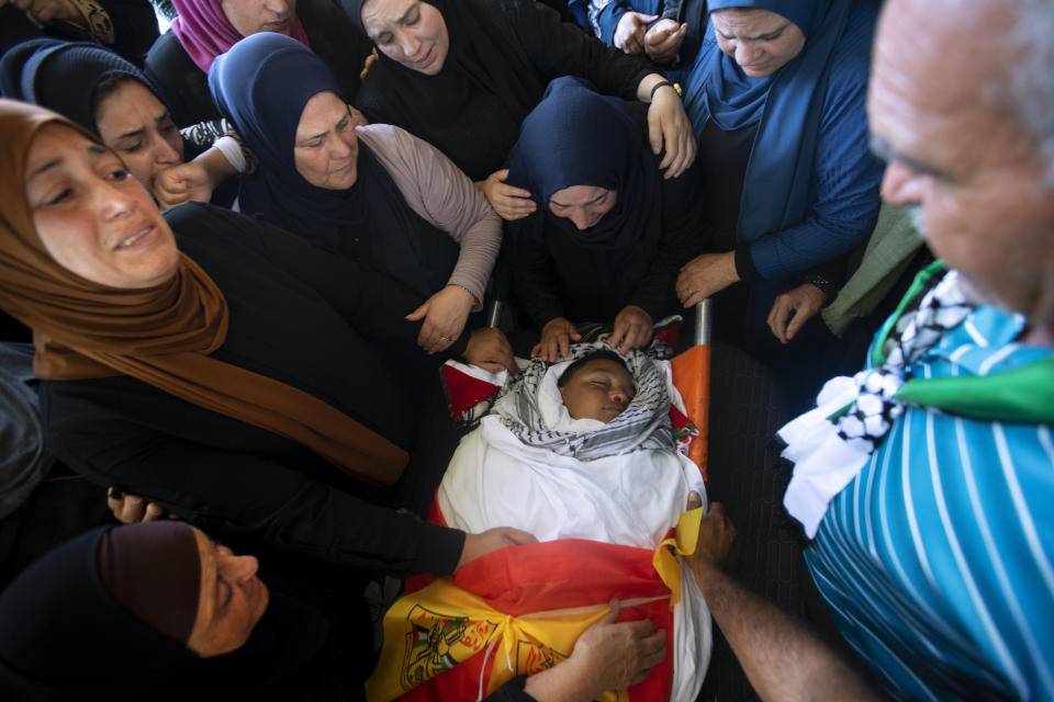 Palestinians mourn around the body of Mohammed al-Alami, 12, during his funeral in the village of Beit Ummar, near the West Bank city of Hebron, Thursday, July 29, 2021. Villagers say the boy was fatally shot by Israeli troops while traveling with his father in a car. The Israeli military has launched an investigation into the shooting. (AP Photo/Majdi Mohammed)