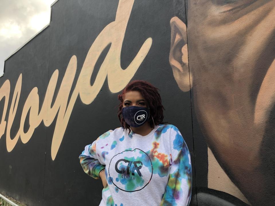 Adriana Holt of Decatur, Ga., stands in front of a mural of George Floyd.