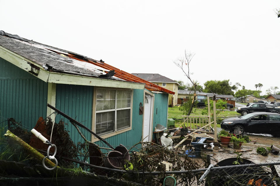 A home is separated from its porch by high winds and pushed into a neighbor's fence Saturday, May 13, 2023, after a tornado touched down in Laguna Heights, Texas. At least one person was killed when a tornado struck an unincorporated community on the Gulf coast near the southern tip of Texas, damaging dozens of homes and knocking down power lines early Saturday, authorities said. (Denise Cathey/The Brownsville Herald via AP)